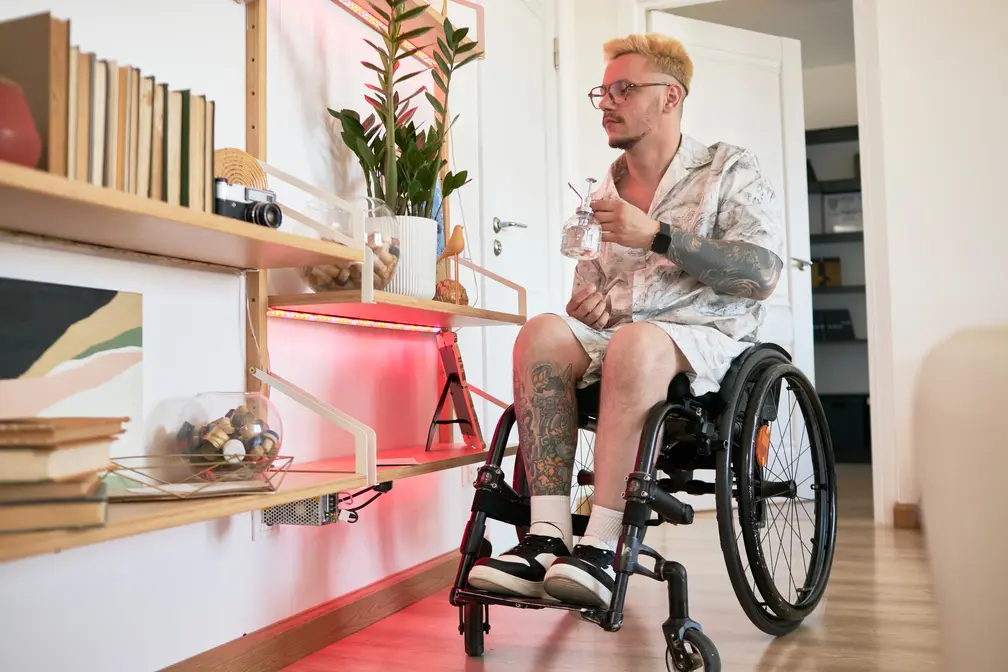 Disabled man in wheelchair watering an indoor plant